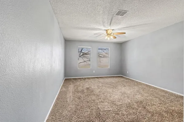 an empty room with windows and fan