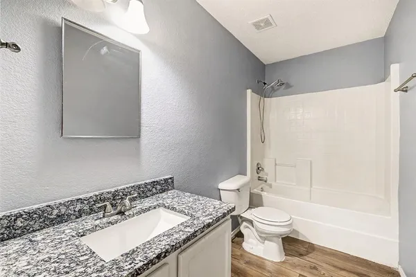 a bathroom with a granite countertop sink toilet and shower