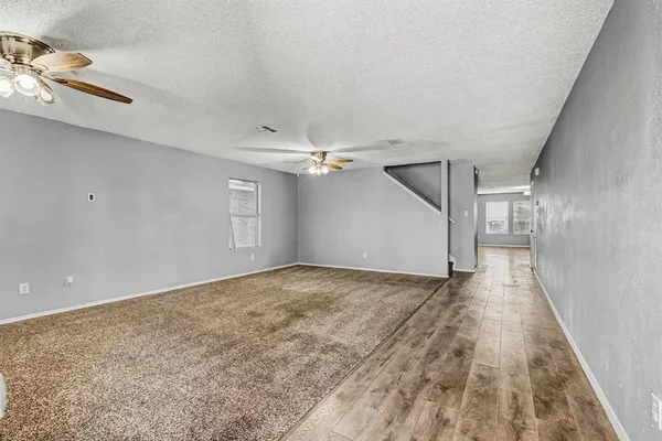 an empty room with a windows and ceiling fan
