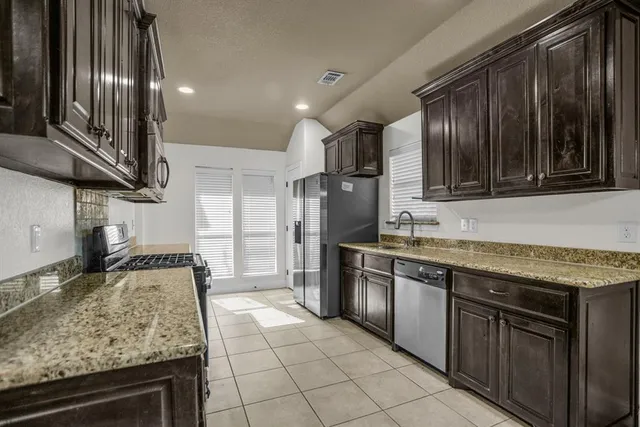 a kitchen with stainless steel appliances granite countertop a stove top oven a sink and dishwasher