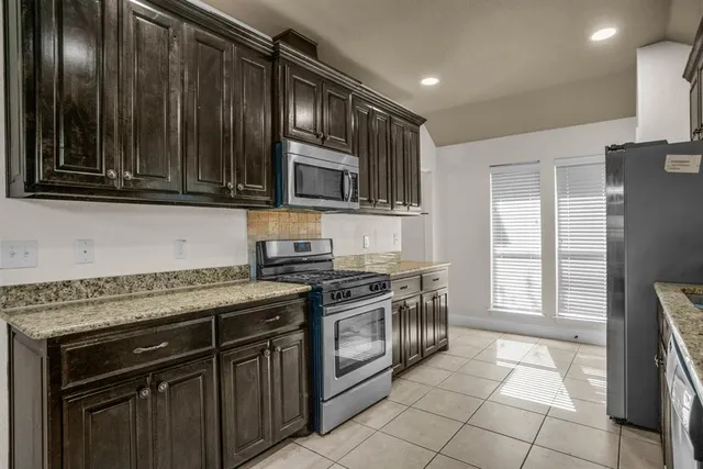 a kitchen with granite countertop a stove top oven microwave and cabinets