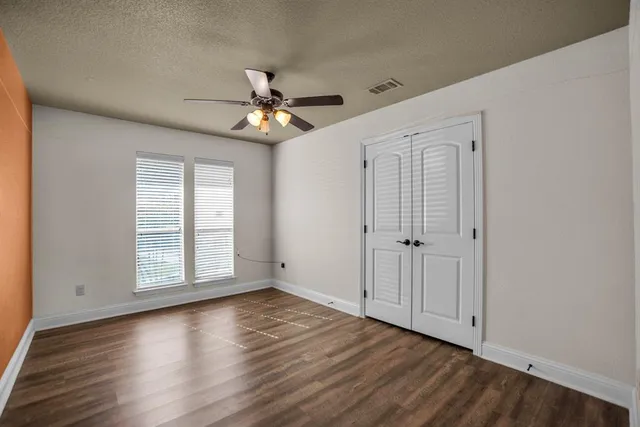 a view of empty room with wooden floor and fan