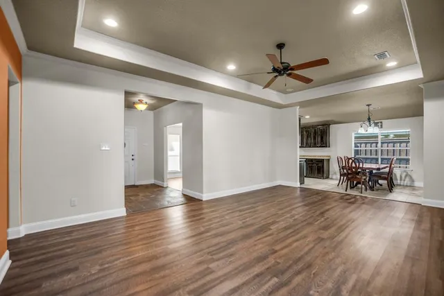 an empty room with wooden floor and a ceiling fan