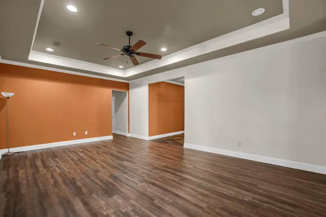 a view of an empty room with wooden floor and a ceiling fan
