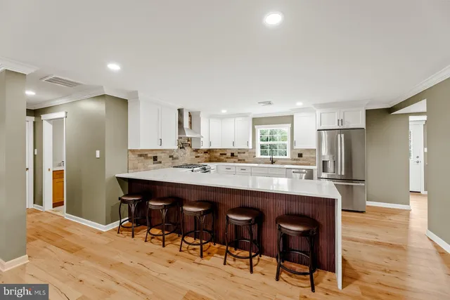 a kitchen with stainless steel appliances kitchen island granite countertop a table chairs sink and cabinets