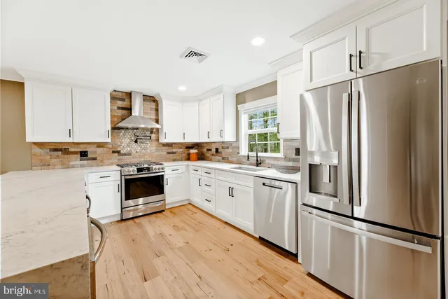 a kitchen with white cabinets stainless steel appliances and window