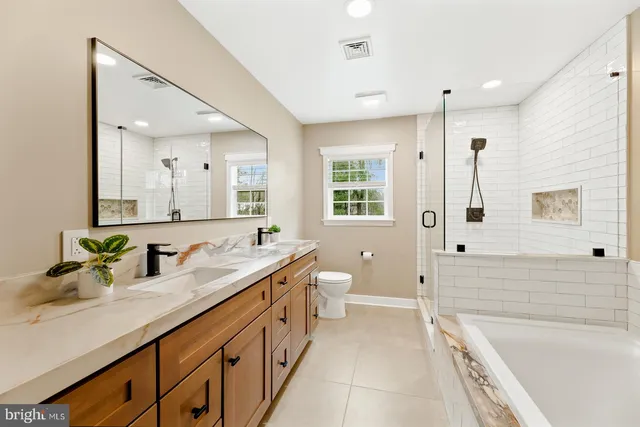 a spacious bathroom with a double vanity sink a mirror a bathtub and next to a window
