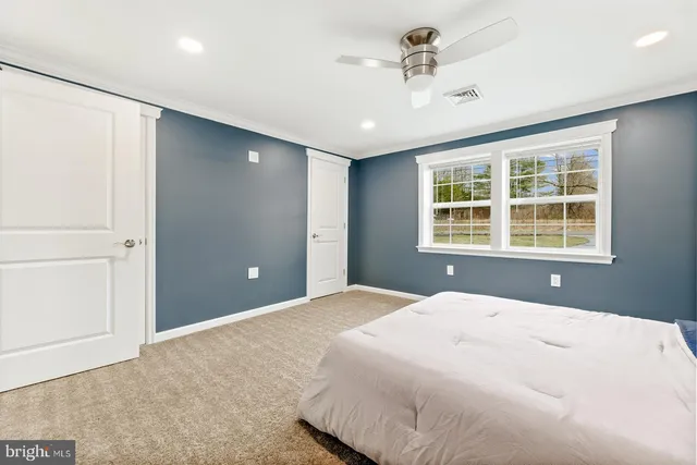 a bedroom with a large bed and chandelier fan