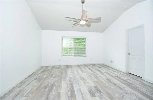 an empty room with wooden floor chandelier fan and windows