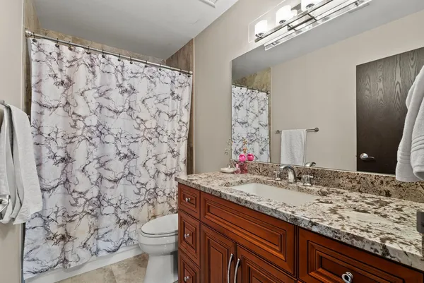 a bathroom with a granite countertop sink a toilet and a mirror