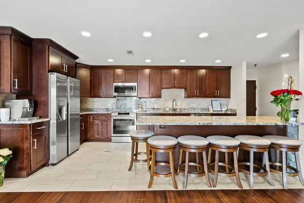 a kitchen with stainless steel appliances granite countertop a table chairs sink refrigerator and microwave