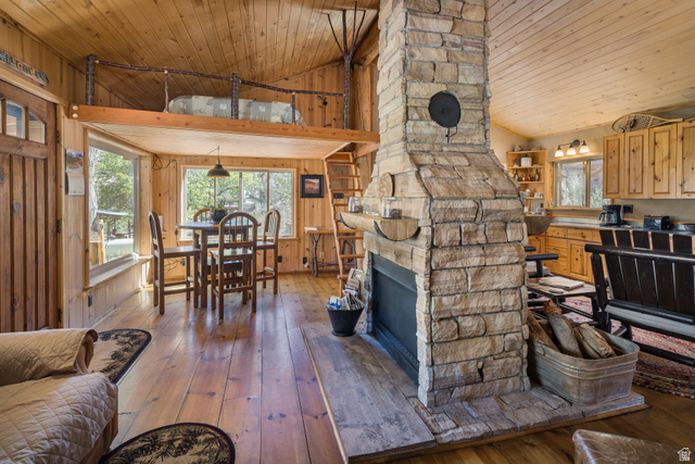 1035 Montezuma Creek Road Monticello, UT 84535 - Photo 24 of 27 Stone-clad fireplace with hearth, wood-finish flooring, wood-paneled walls and ceiling, built-in kitchen cabinetry, and an upper loft area