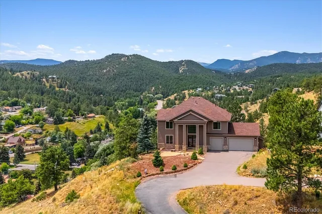 a front view of a house with a yard and mountain