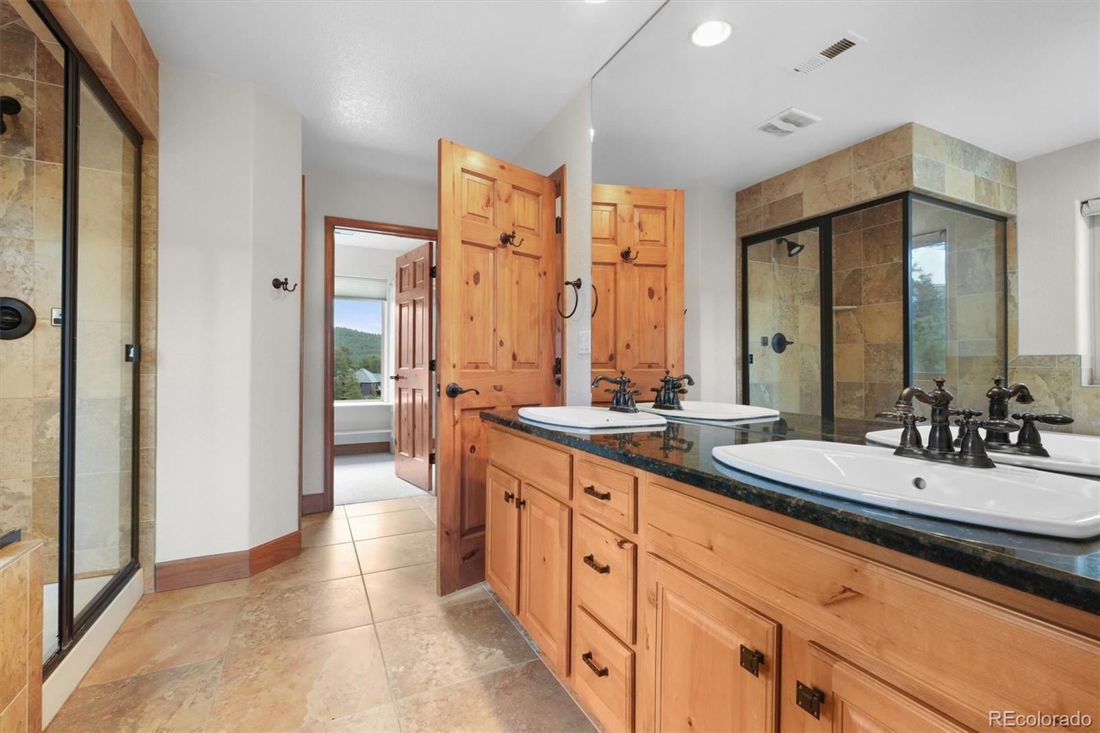 3191 Bittersweet Lane Evergreen, CO 80439 - Photo 14 of 40 a spacious bathroom with a double vanity sink a mirror and a shower