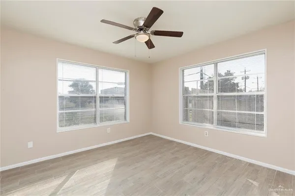 a view of an empty room with a window and wooden floor