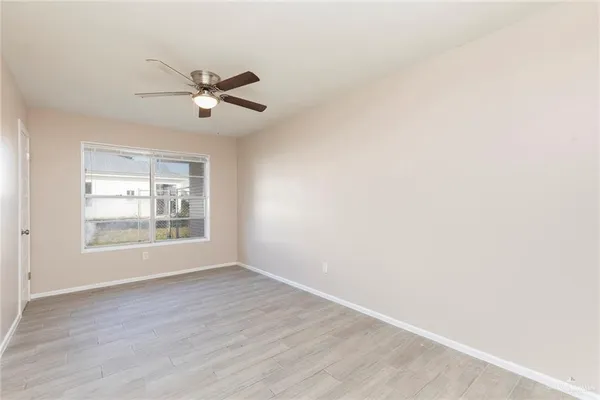 a view of an empty room with wooden floor and a window