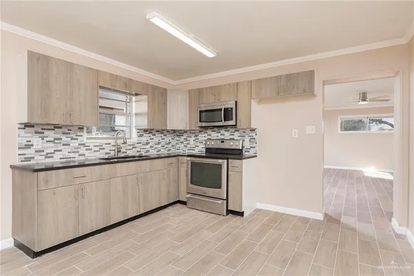 a kitchen with granite countertop a sink cabinets and stainless steel appliances