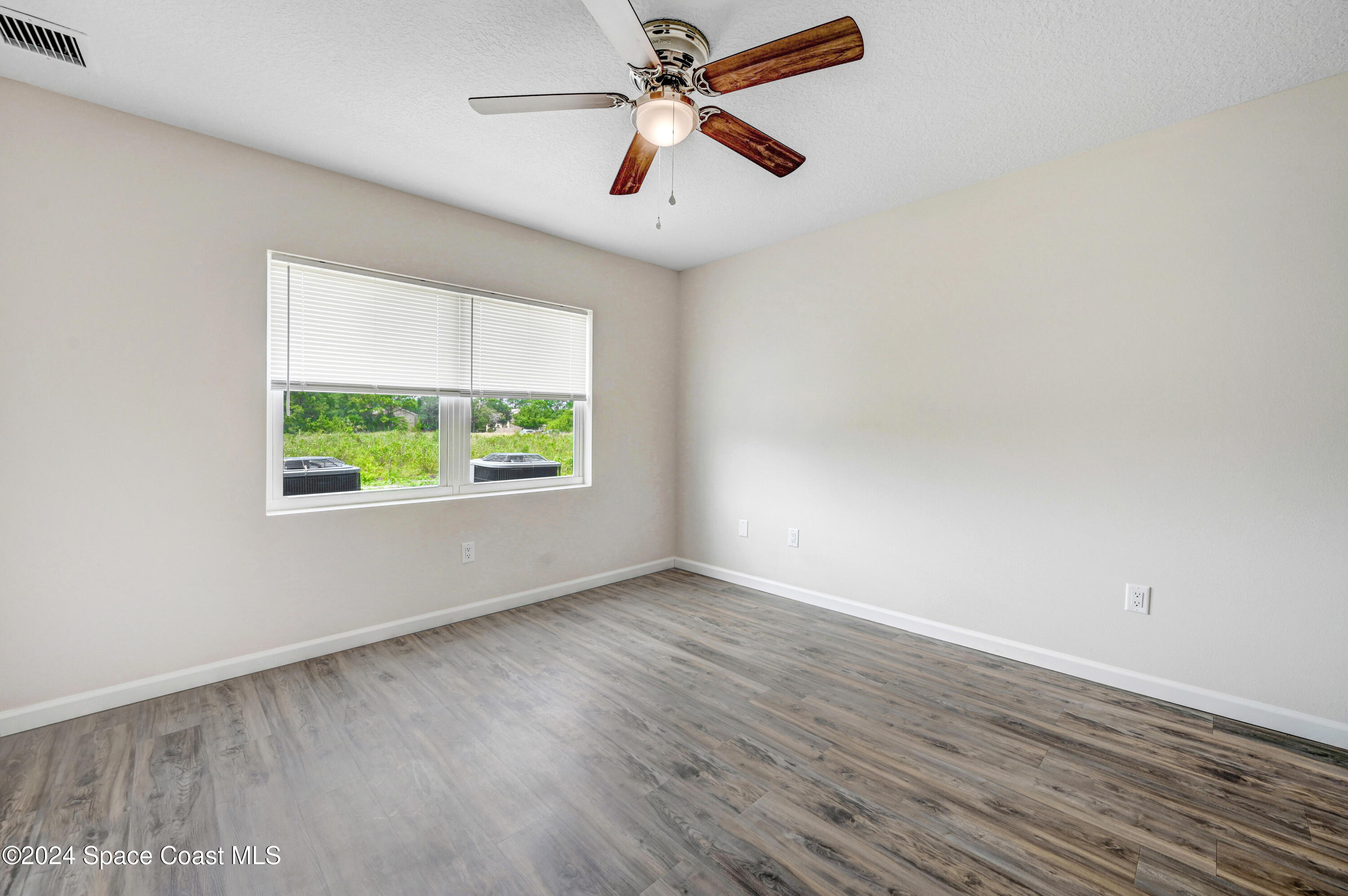 1895 Convair Street Southeast, Unit 2102 Palm Bay, FL 32909 - Photo 16 of 16 an empty room with wooden floor ceiling fan and windows