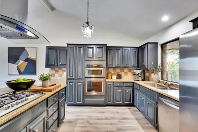 a kitchen with stainless steel appliances granite countertop a stove a sink and a refrigerator