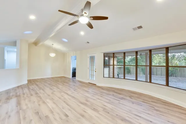 a view of an empty room with a window and a ceiling fan