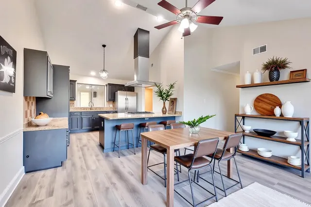 a kitchen with stainless steel appliances granite countertop a stove a refrigerator a dining table and chairs with wooden floor