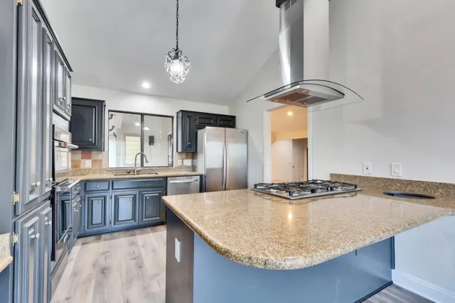 a kitchen with stainless steel appliances granite countertop a sink a stove and refrigerator