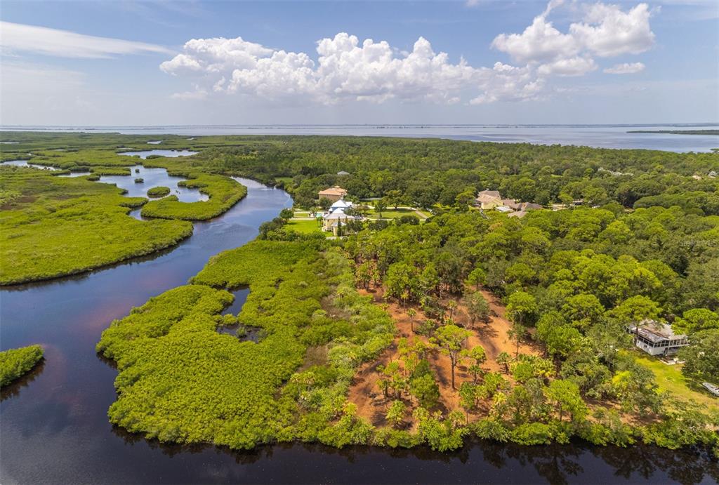 Aerial view of entire property from north to south, with waterfront on north and east boundaries, and Tampa Bay in the background