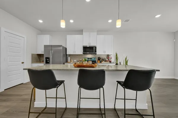 an empty room with wooden floor ceiling fan and windows