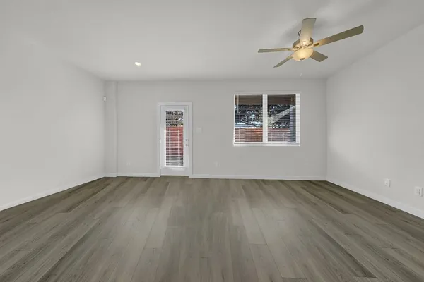 a view of an empty room with a window and wooden floor