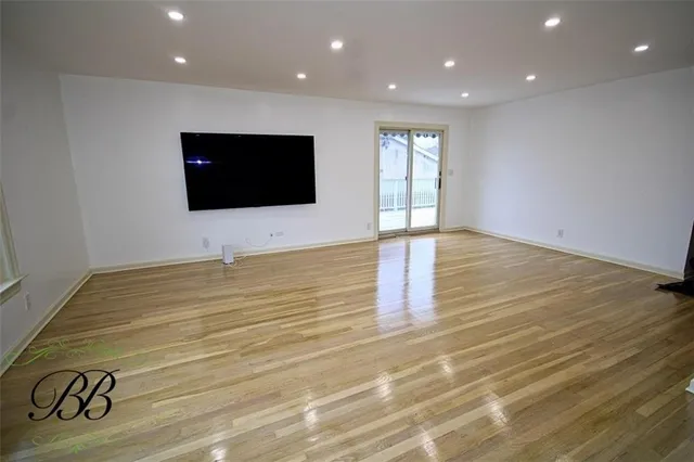 a view of an empty room with wooden floor and windows
