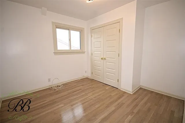 an empty room with wooden floor cabinet and windows