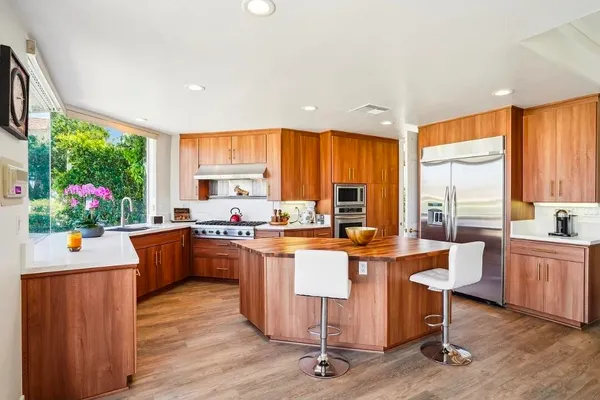 a kitchen with stainless steel appliances granite countertop a stove a sink dishwasher and a dining table with garden view