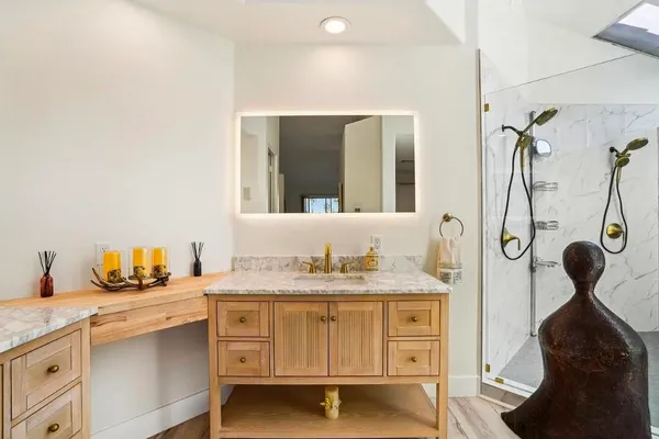 a bathroom with a granite countertop sink a mirror and shower