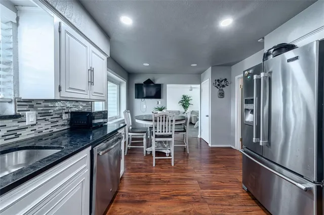 a kitchen with stainless steel appliances granite countertop a table chairs microwave and sink
