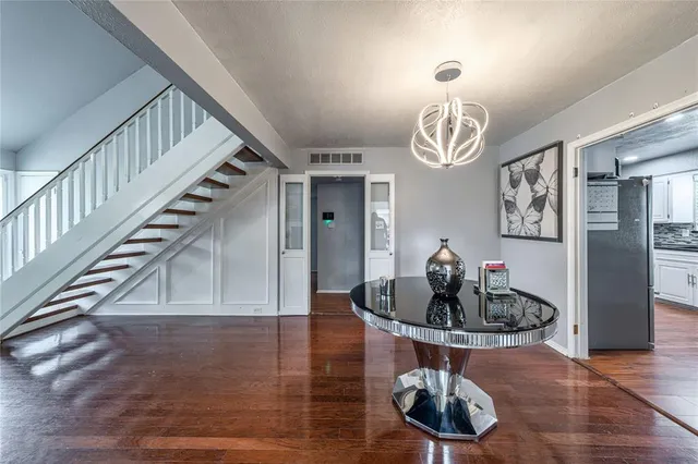 a dining room with wooden floor a chandelier and kitchen view