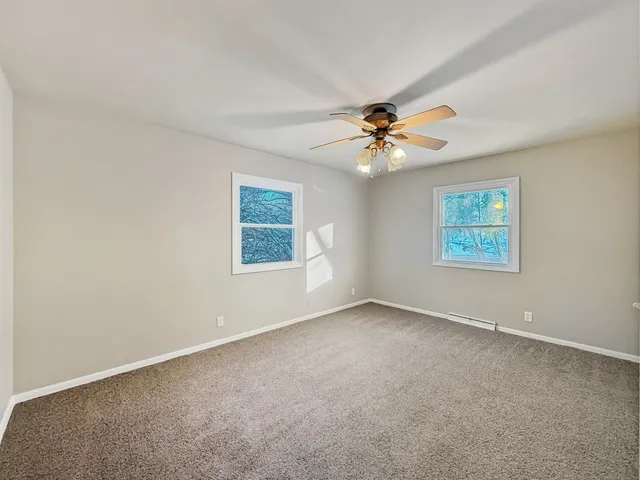 an empty room with windows and chandelier fan