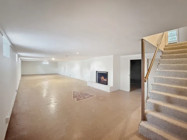 a view of an empty room with wooden floor and stairs