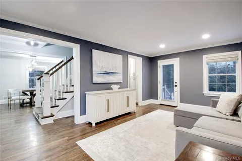 a living room with furniture and stairs with wooden floor