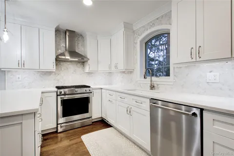 a kitchen with stainless steel appliances granite countertop a stove a sink and a white cabinets