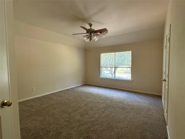 an empty room with windows and fan
