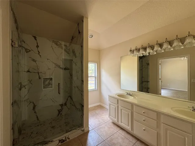 a bathroom with a granite countertop sink a mirror and shower