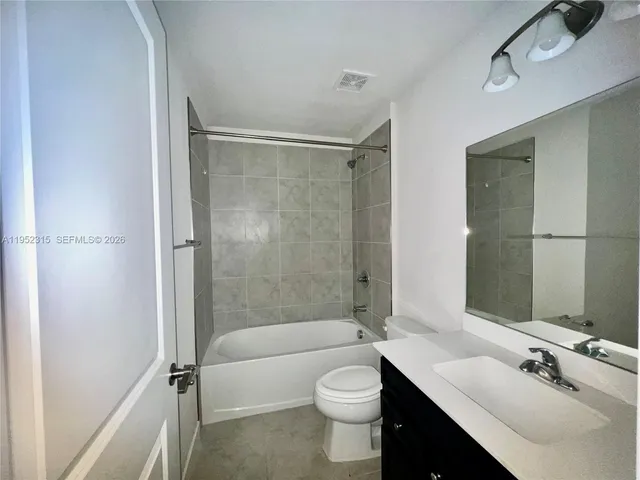 a bathroom with a bathtub shower sink mirror vanity and toilet