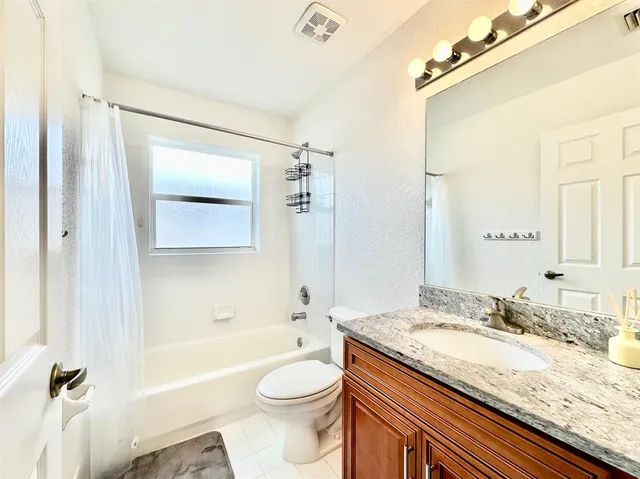 a bathroom with a granite countertop sink toilet mirror and bathtub