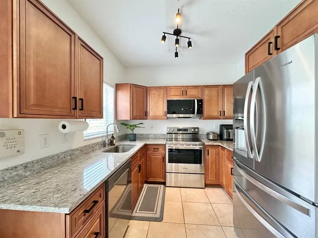 a kitchen with stainless steel appliances granite countertop a sink stove microwave and refrigerator