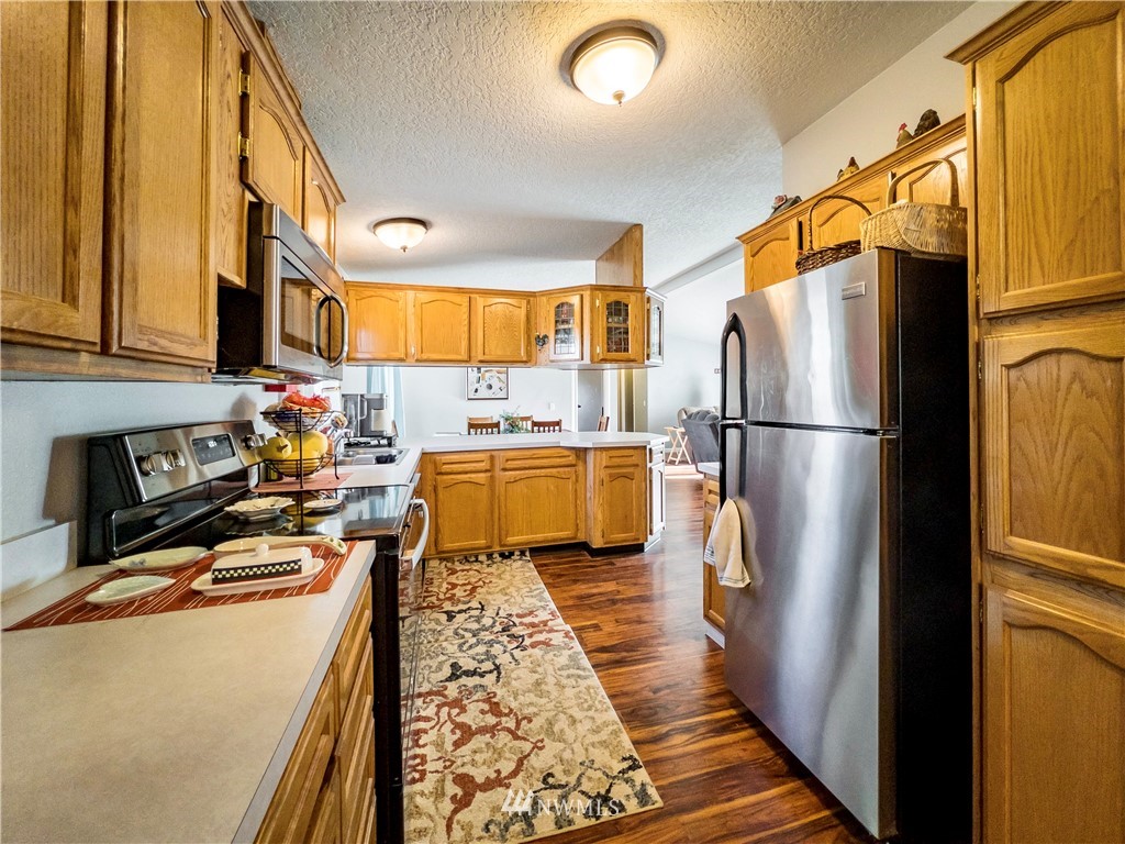 291 Spencer Road Sequim, WA 98382 - Photo 10 of 24 a kitchen with a refrigerator a stove top oven and a dining table