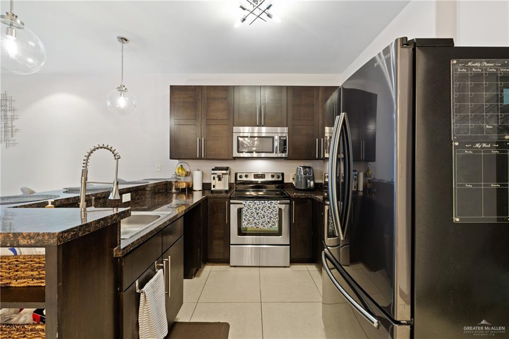 813 Travis Street, Unit 203 Mission, TX 78572 - Photo 9 of 30 a kitchen with stainless steel appliances granite countertop a refrigerator a stove and a sink