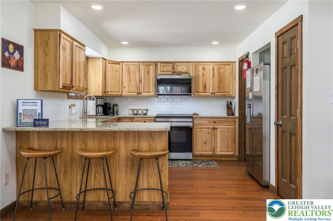 2206 Chatham Court Bushkill, PA 18324 - Photo 5 of 45 a kitchen with stainless steel appliances granite countertop a stove top oven a sink dishwasher and a refrigerator with wooden floor