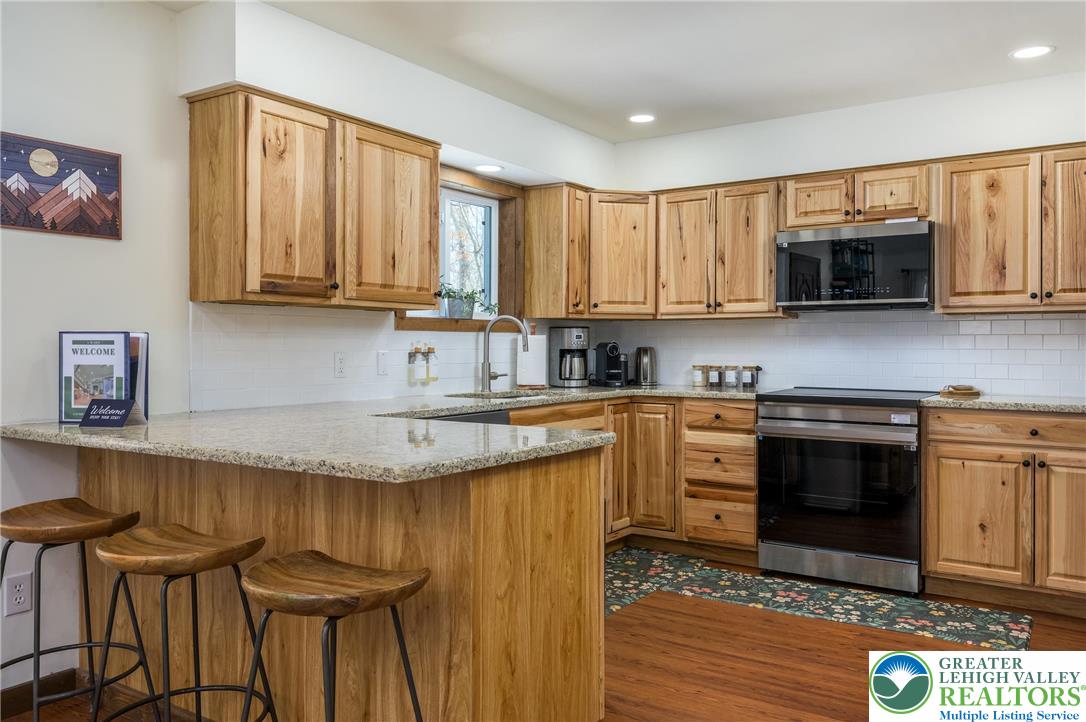 2206 Chatham Court Bushkill, PA 18324 - Photo 6 of 45 a kitchen with granite countertop a stove a sink and a microwave
