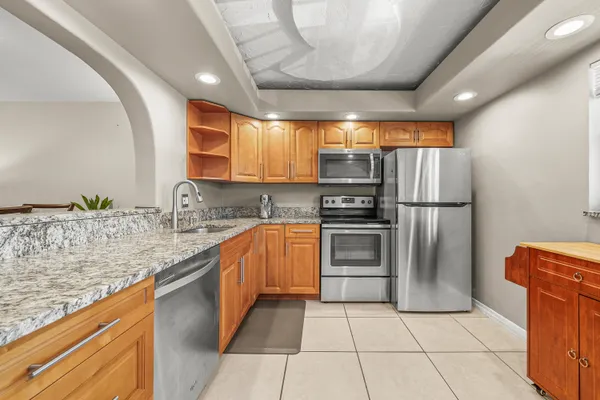 a kitchen with stainless steel appliances granite countertop a refrigerator a sink and a stove