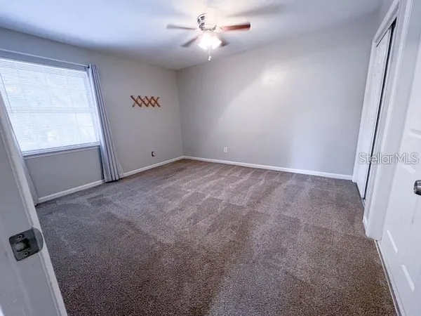 an empty room with windows and fan